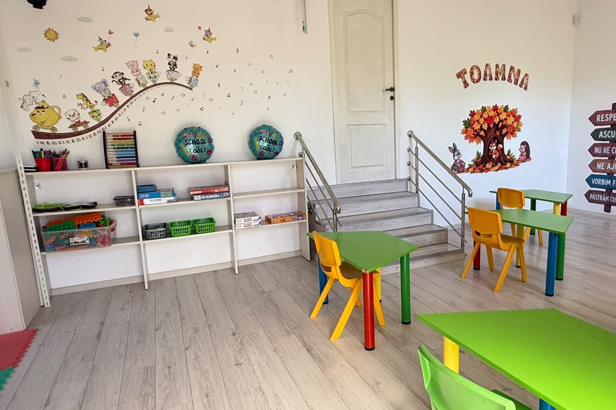 Sala de afterschool, cu mese colorate și rafturi cu jocuri